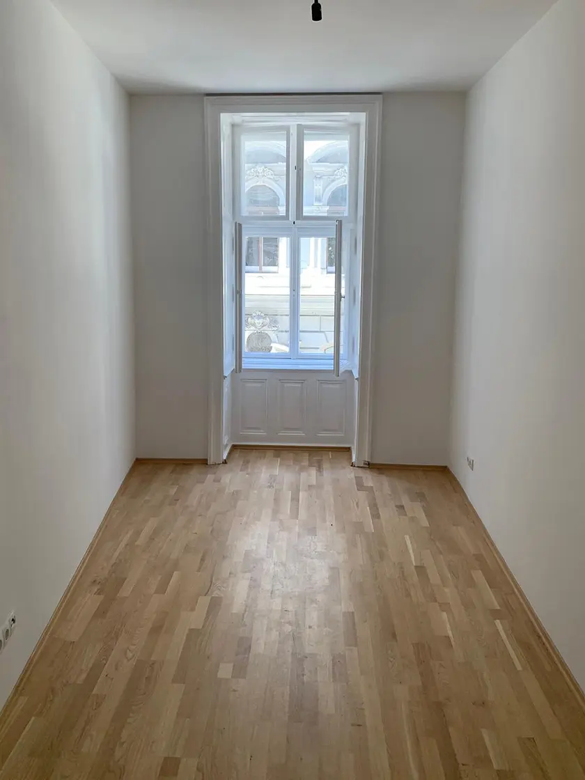 Sanierte Altbauwohnung in Wien mit neuem Parkett und hellen Wänden, umgesetzt von emasan